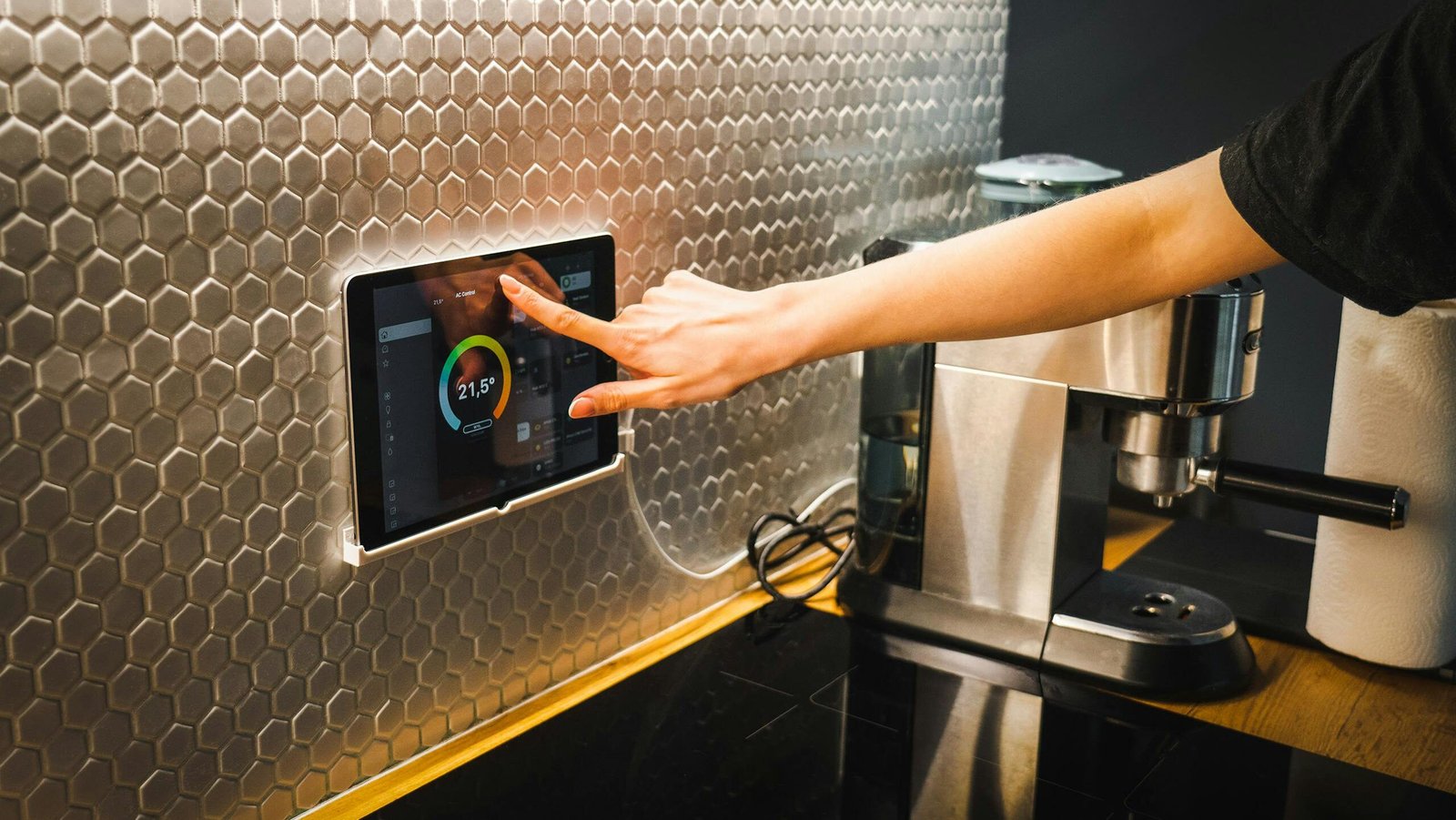 Una cocina moderna con una mano que usa una tableta para controlar un sistema de hogar inteligente.